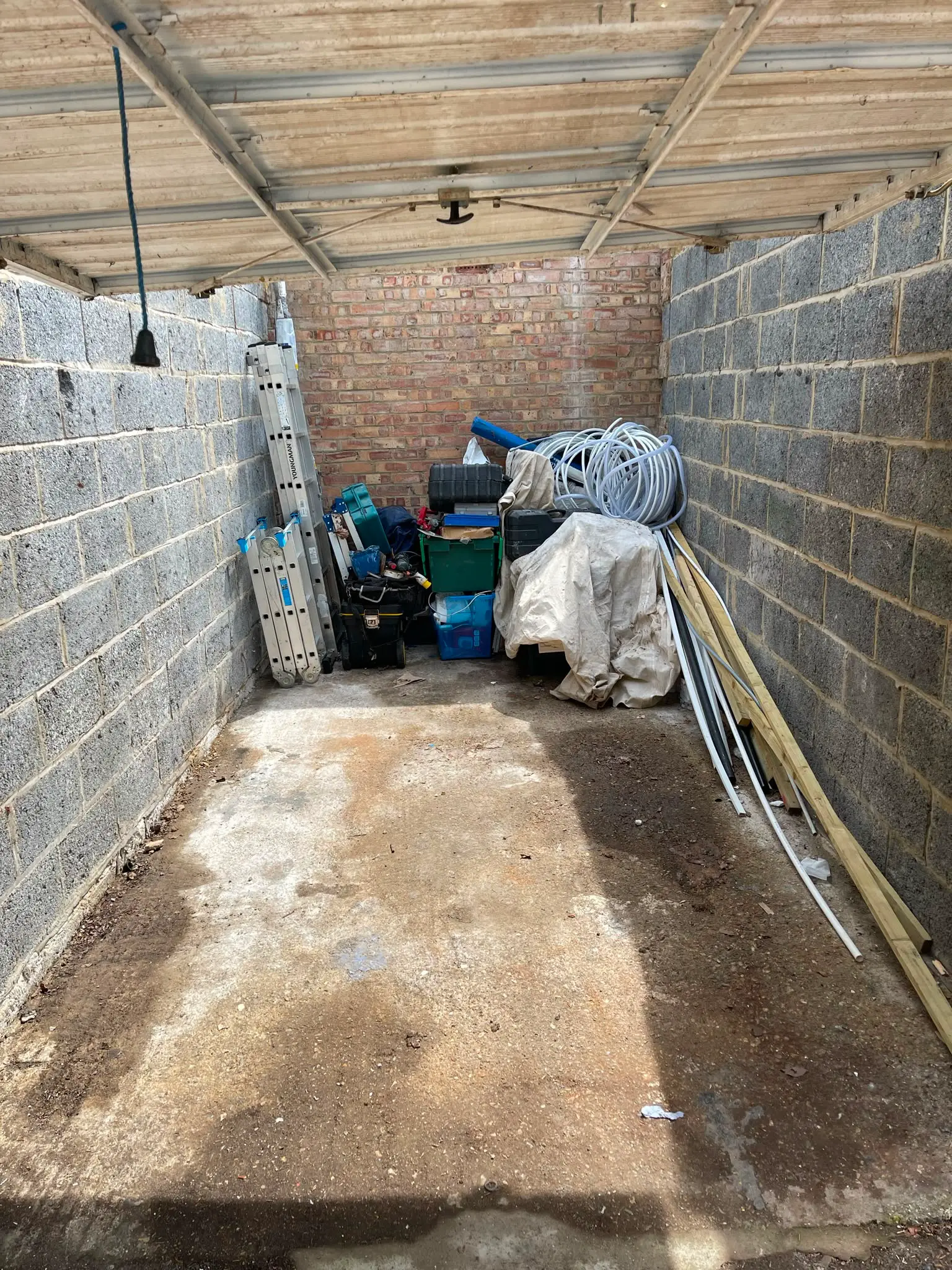 Garage cleared and swept, with only ladders, boxes and timber left along the back wall.