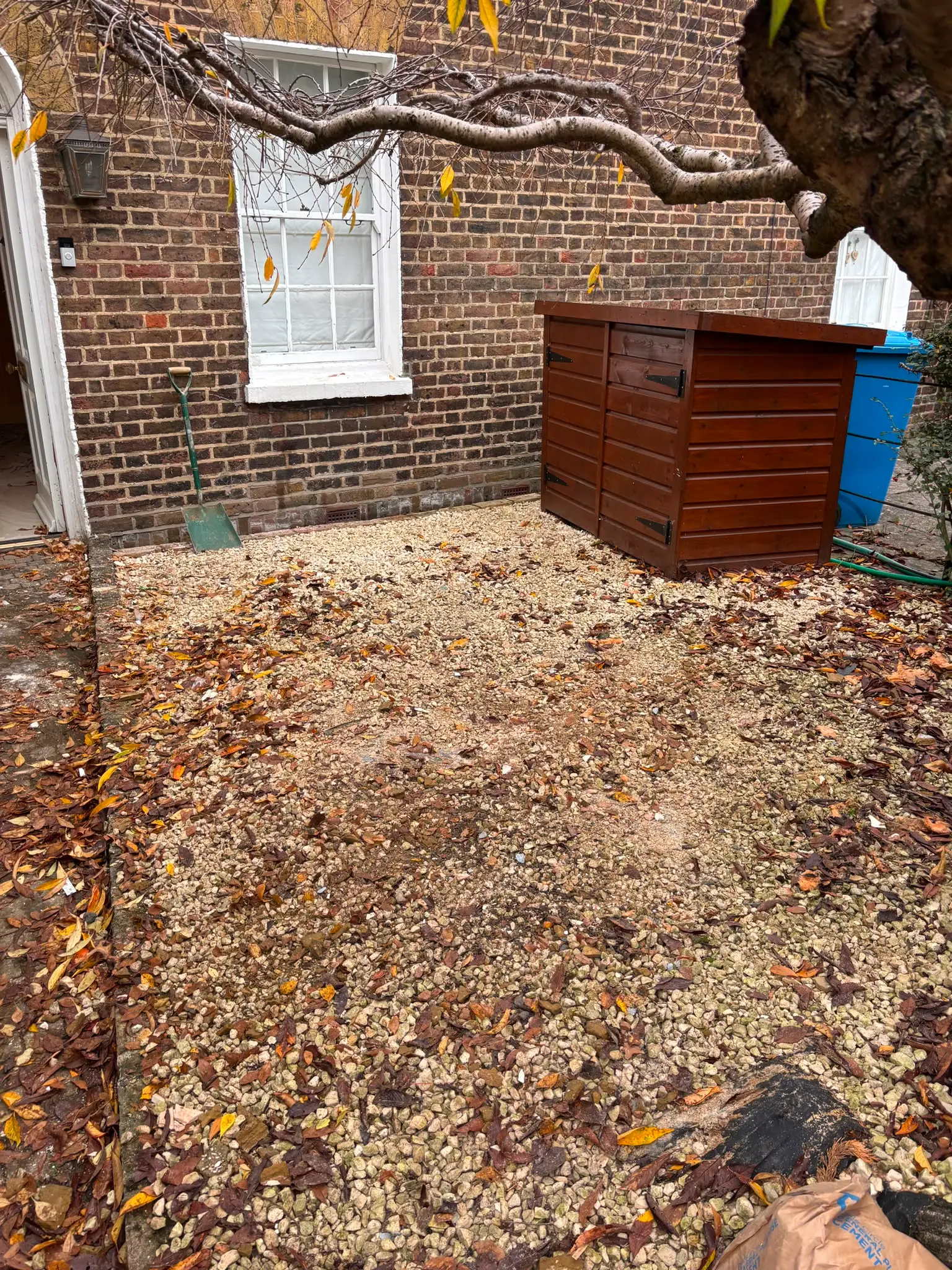 The same courtyard cleared back to gravel, with the bin store and wall clear again.