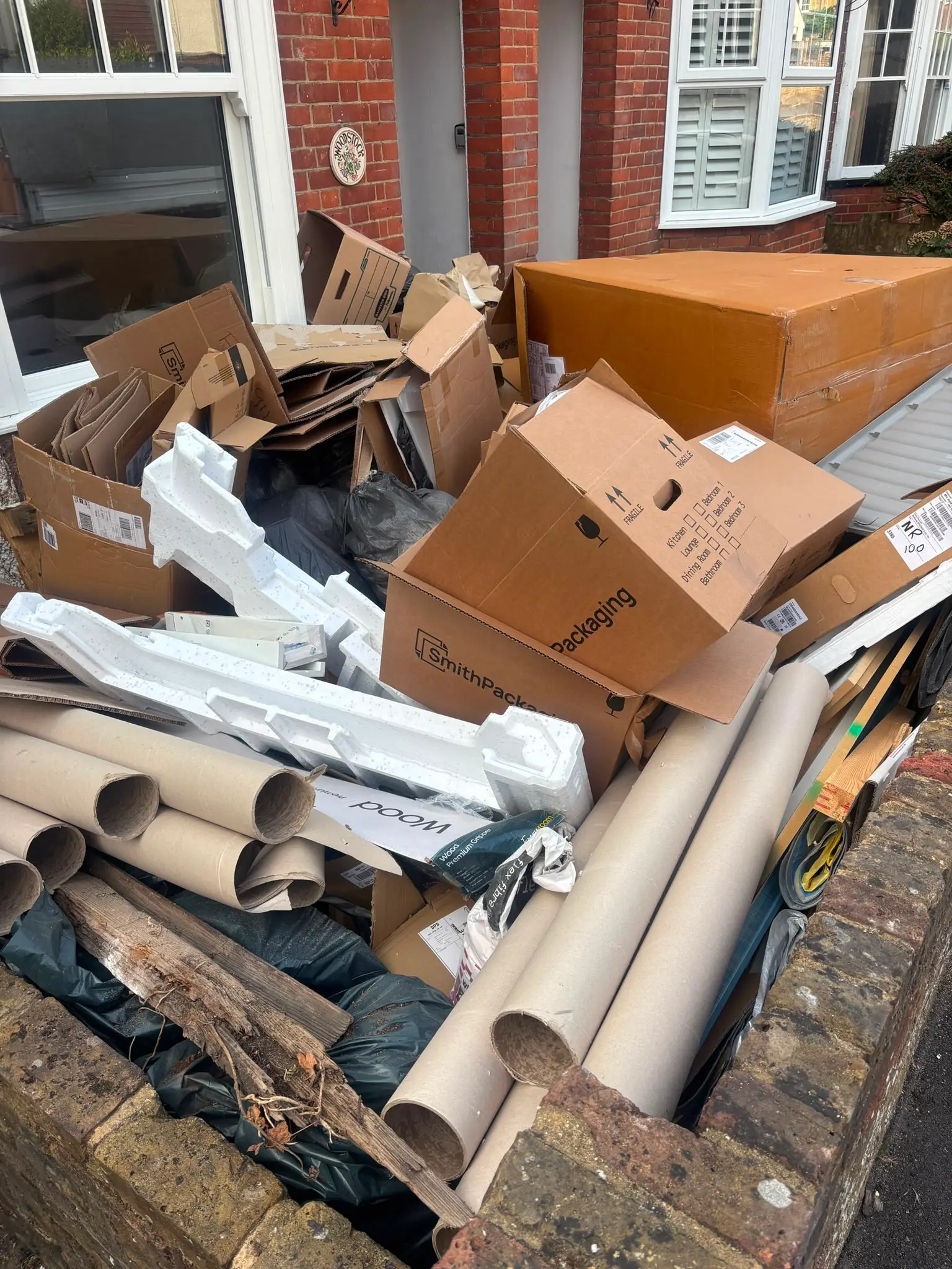 Cardboard boxes, packaging tubes and polystyrene piled in a terraced house front garden before clearance.