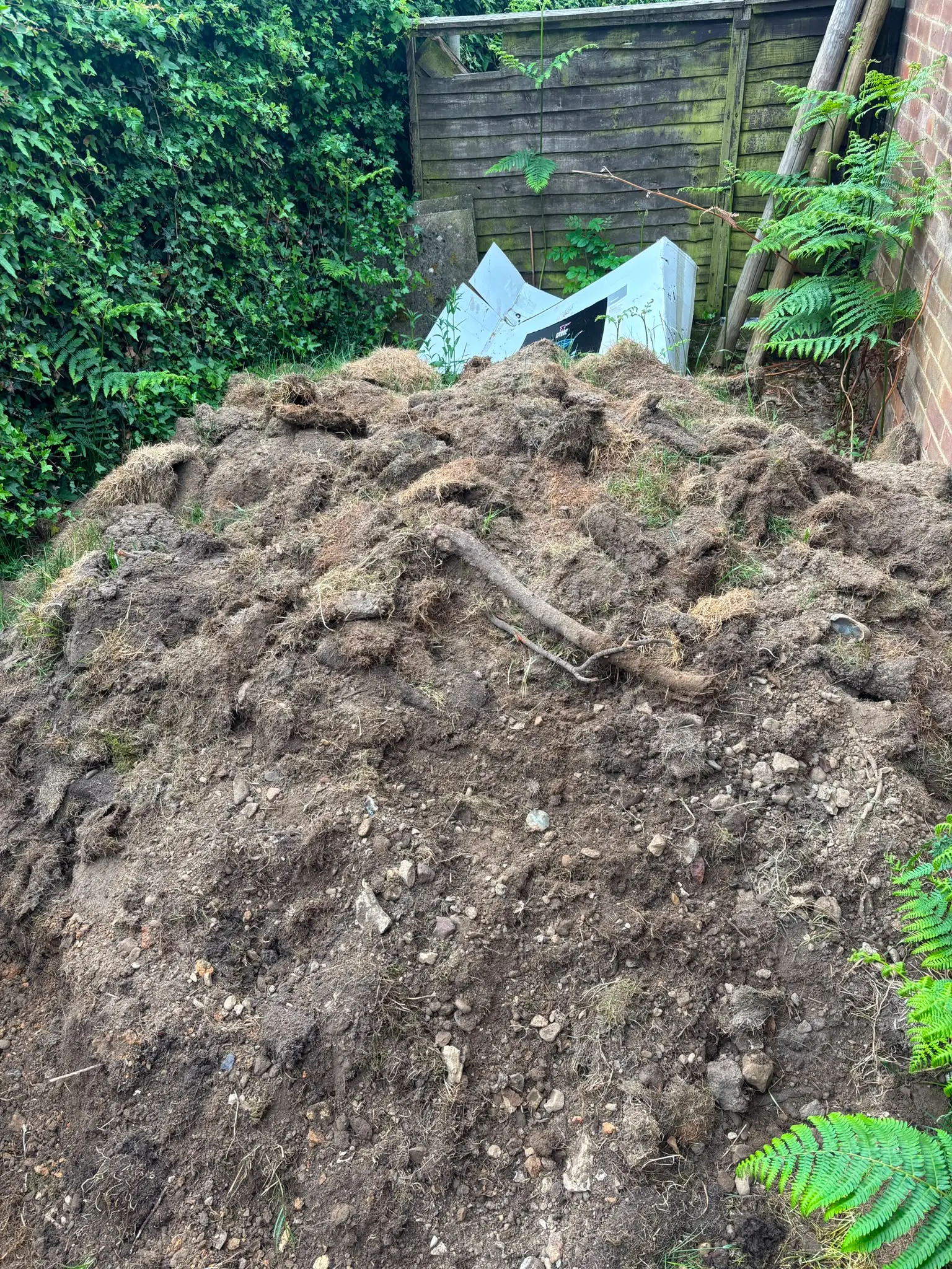 Large pile of soil in a residential garden.