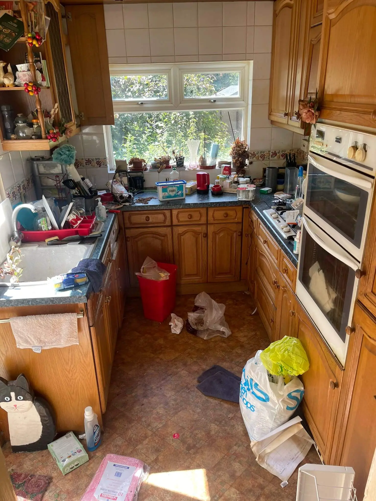 Cluttered kitchen with household items and loose waste before clearance.