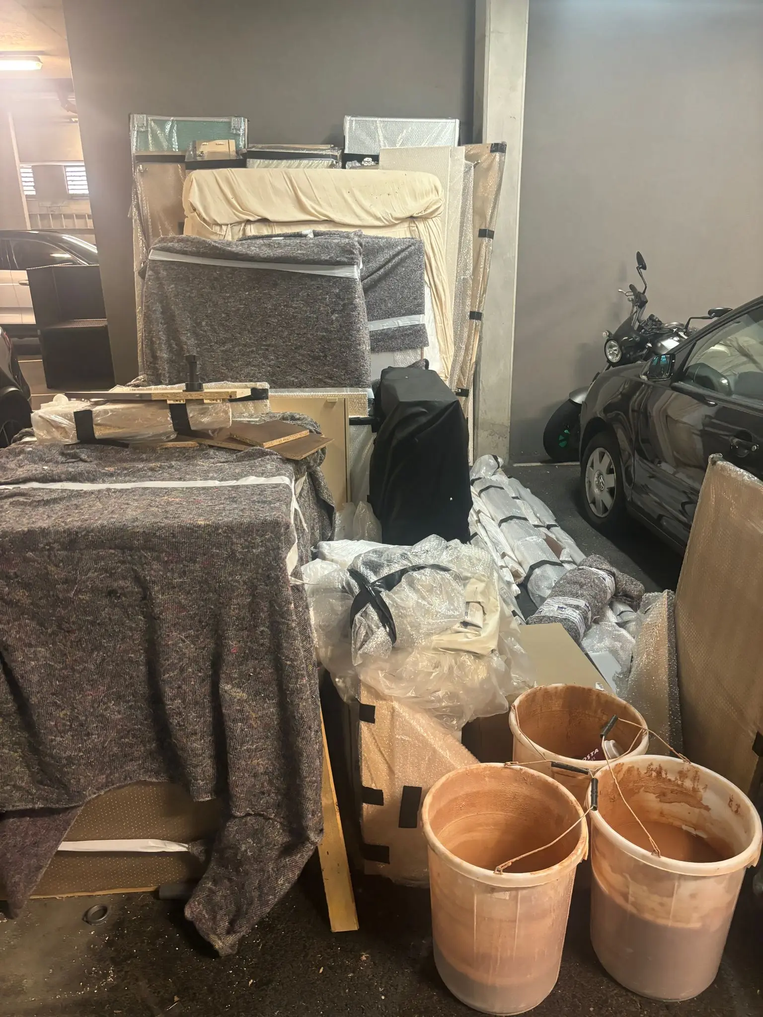 Parking bay filled with wrapped furniture, equipment and containers before clearance.