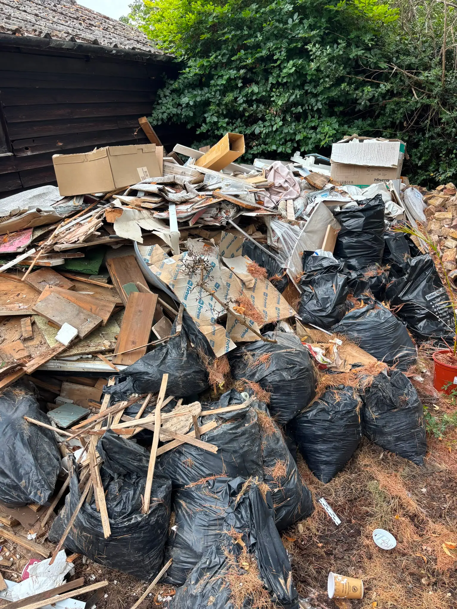 Mixed timber and outdoor waste gathered for removal from a garden.