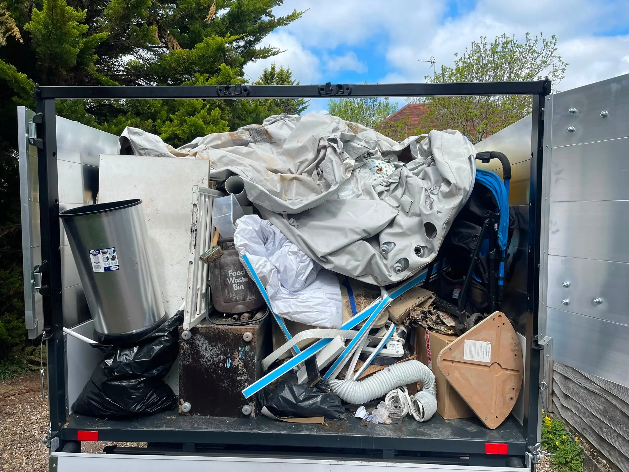 Clearance vehicle loaded with household items, packaging and bagged waste ready for disposal.